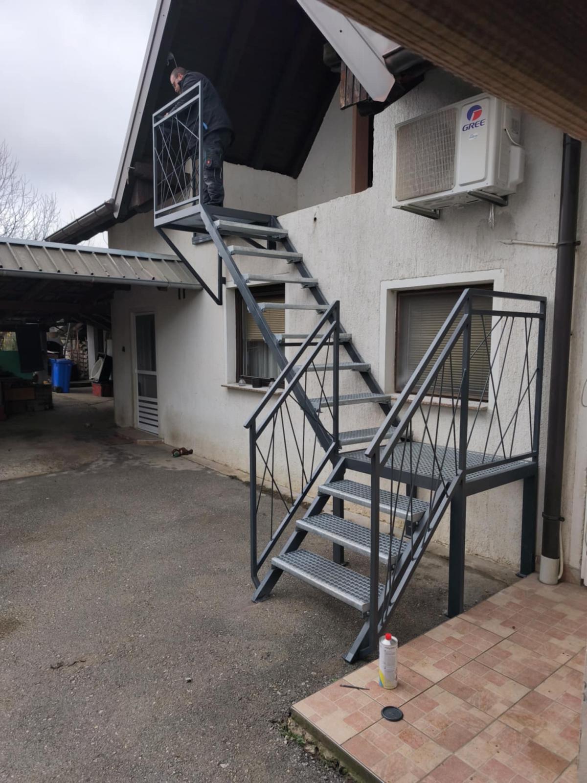 Vanjske čelične stepenice s podestom, rešetkastim gazištima i zaštitnom ogradom.